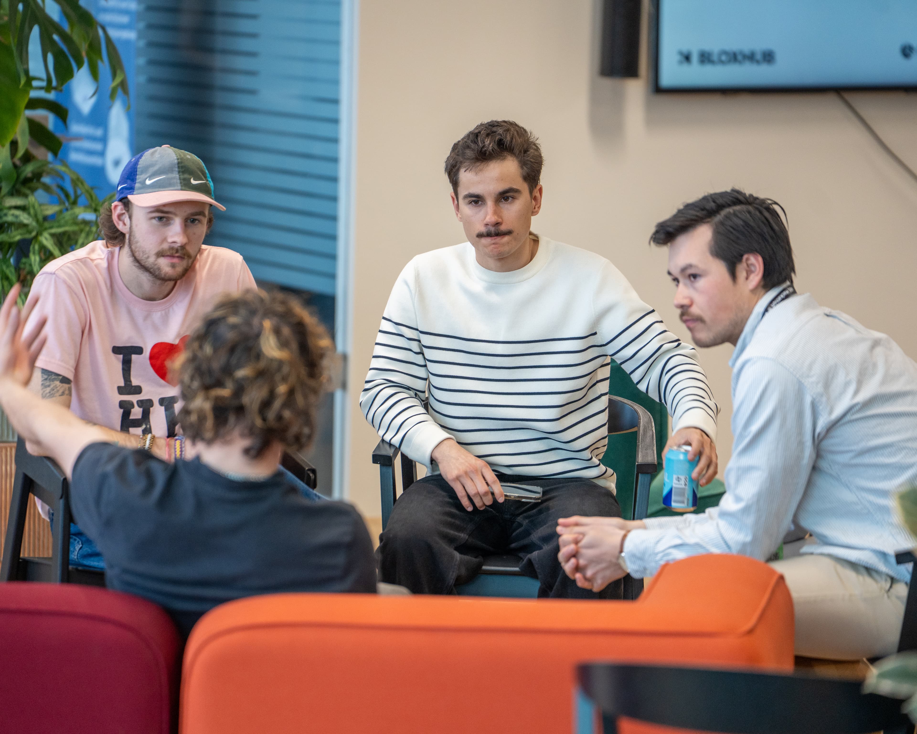 Team Klaudiush in conversation at BLOXHUB Copenhagen — informal working session, BLOXHUB screen visible in the background
